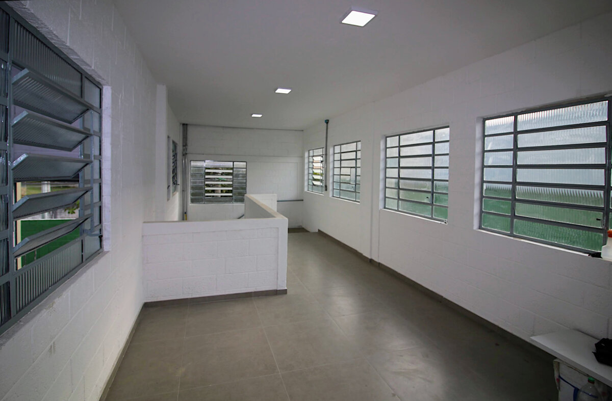 recepção de acesso pela escada na sala principal do escritório,  com janelas basculantes para o exterior e para o interior do galpão.