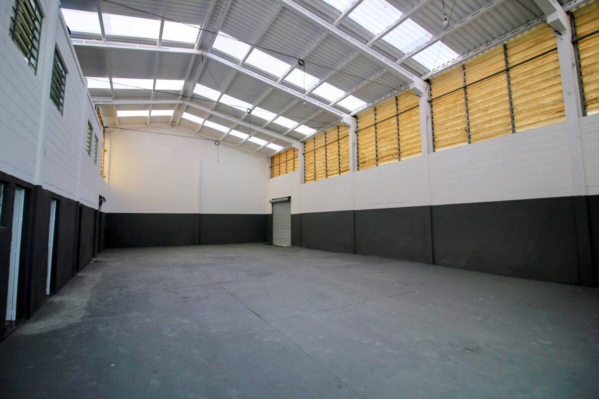 Vista interior de galpão com iluminação zenital por telhas translúcidas.